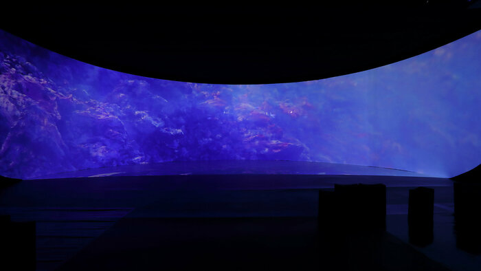 Foto des Videobeitrags "Life Beyond" des Künstlers Kay Walkowiak im mobilen Pavillon, zu sehen ist eine vulkanische Landschaft