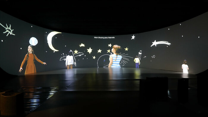Ausstellungsansicht: Video mit Kindern vor gezeichneten Weltraummotiven